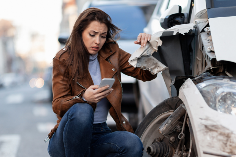Woman inspecting damage after a car crash